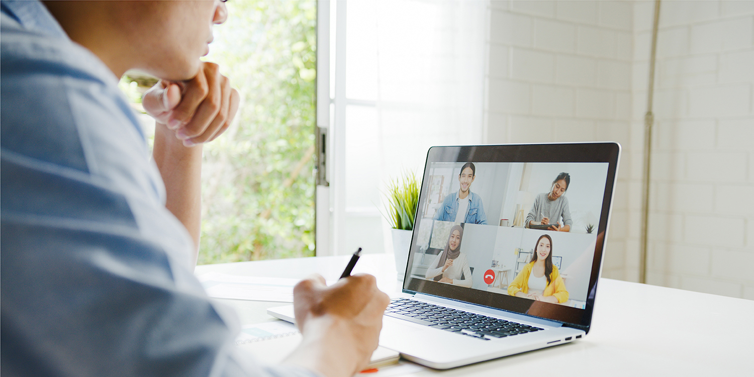 asian man looking onto laptop in online rooflight meeting