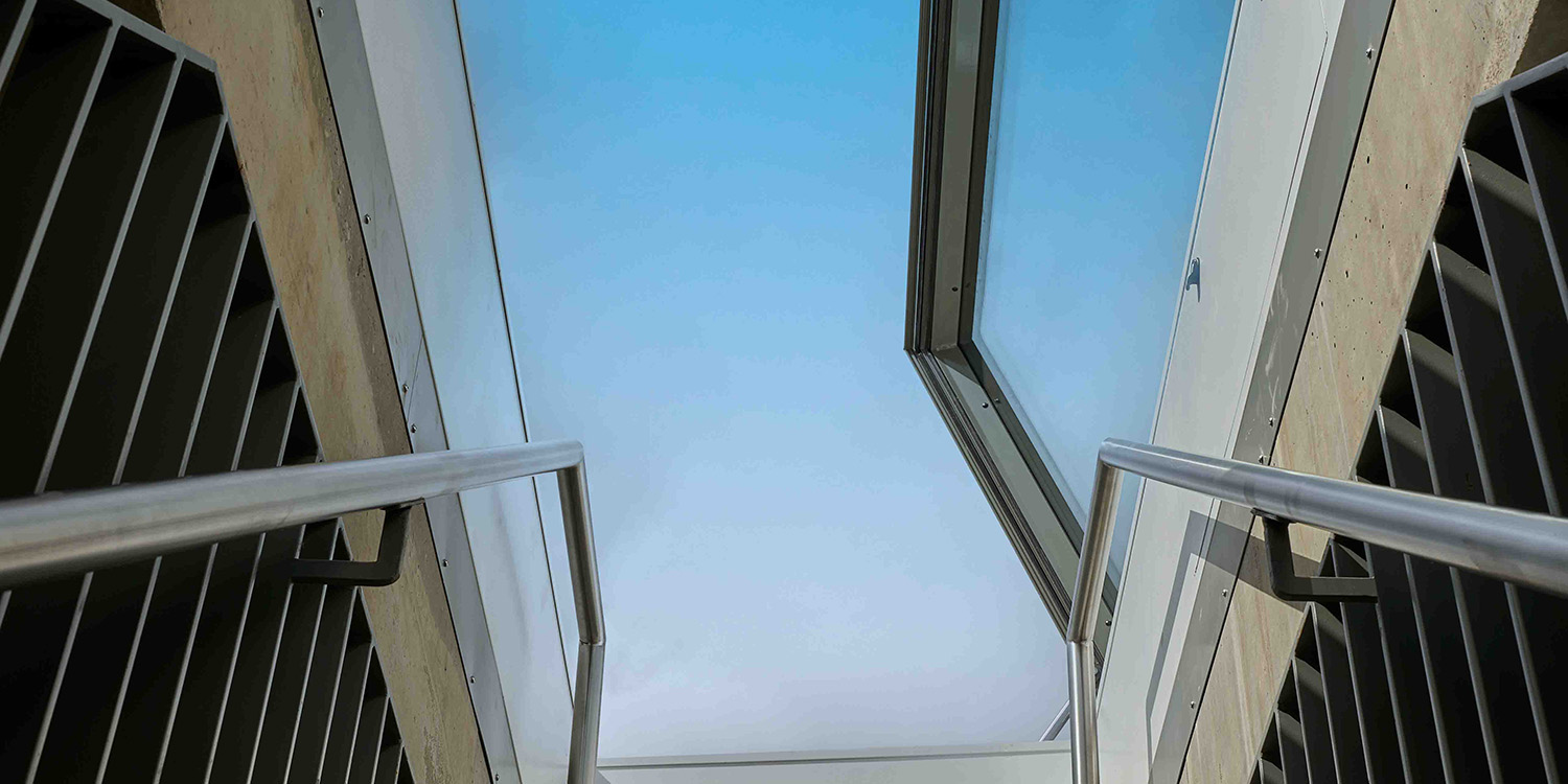 looing up stairs to a glass roof access hatch opening